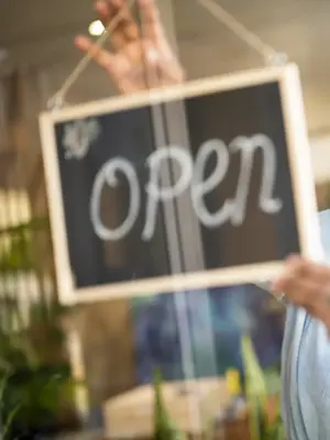 person hanging an open sign in the window
